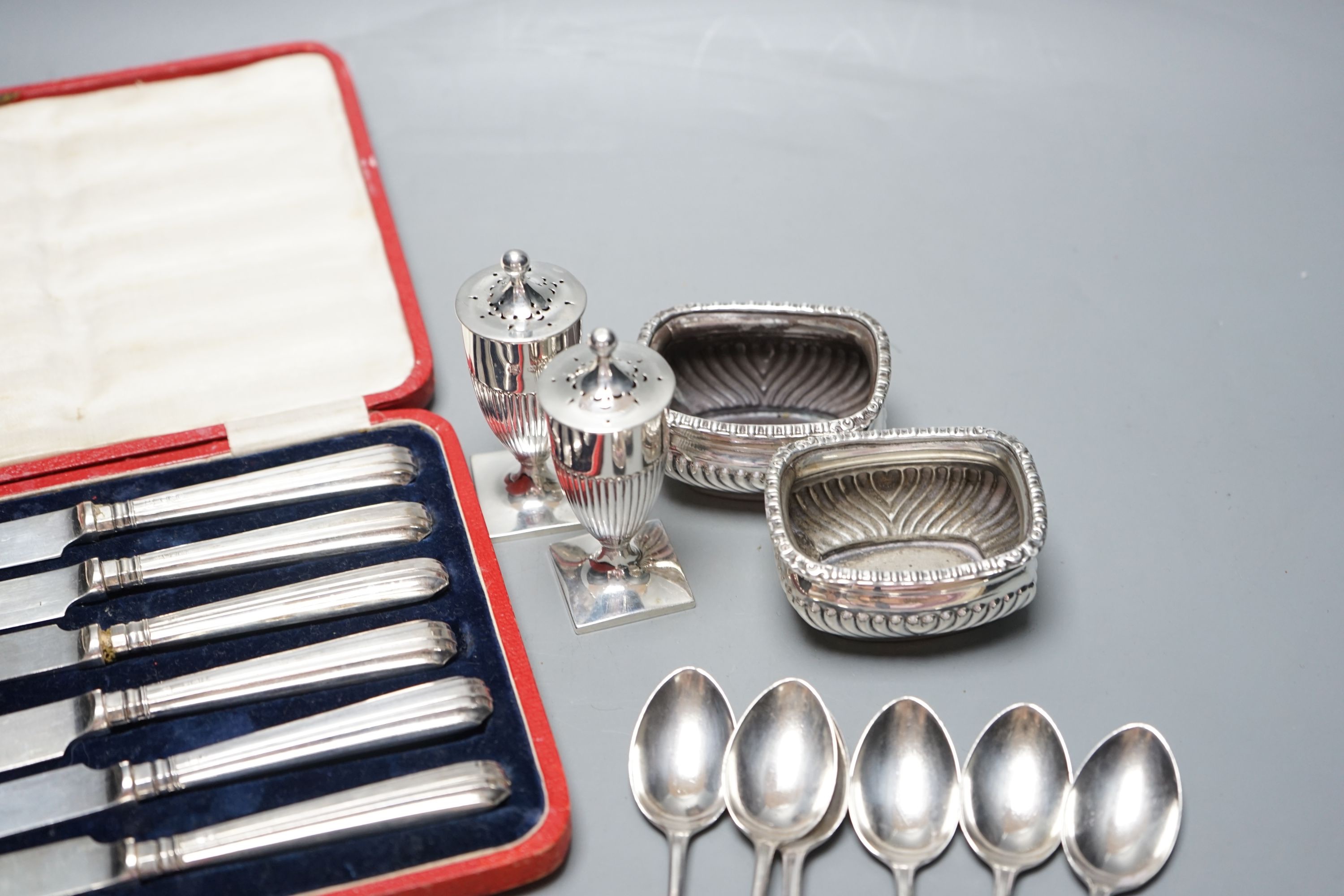 A pair of Victorian silver pepperettes, a pair of later silver salts, six silver teaspoons, a silver dessert knife and a cased set of silver handled tea knives.